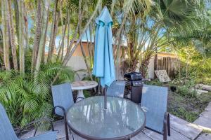 une table et des chaises en verre avec un parapluie bleu dans l'établissement Pet Friendly Pool Home in Hollywood 8 min to Beach, à Hollywood