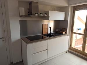 una cucina con mobili bianchi, un lavandino e una finestra di stefy bilo fronte mare ad Alba Adriatica