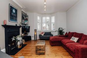 sala de estar con sofá rojo y chimenea en Henley Gardens en Henley on Thames