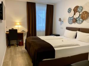ein Hotelzimmer mit einem großen Bett und einem Schreibtisch in der Unterkunft Hotel Royal in Villingen-Schwenningen