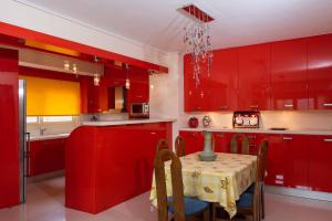 cocina roja con mesa y armarios rojos en Glamour beautique villa, en Acarnas