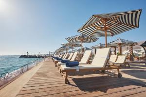 a row of beach chairs and umbrellas on a pier at Tolip Resort El Galala Majestic in Ain Sokhna