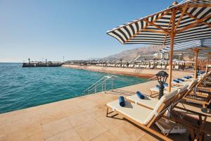 Tolip Resort El Galala Majestic في العين السخنة: صف من الكراسي والمظلات بجانب الماء