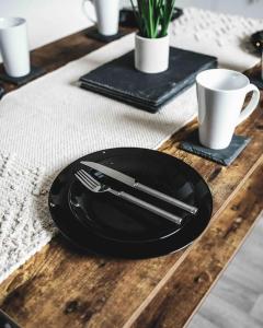 Comfortable Home In Bolton في Farnworth: لوحة سوداء مع سكين وشوكة على طاولة خشبية