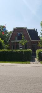 uma casa de tijolos vermelhos com uma bandeira em frente em B en B Op Steendam, Het Voorhuis em Steendam