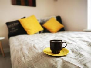a coffee cup on a yellow plate on a bed at Yogi Wellness Guesthouse in Klagstorp