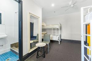 シドニーにあるLondon Plane Backpackersの鏡、テーブル、二段ベッドが備わる客室です。