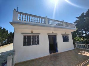 uma pequena casa branca com uma escada em cima em Maison de vacances avec vue sur mer proche Tanger em Alcácer-Ceguer