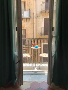 Otwarte drzwi na balkon ze stołem i krzesłami w obiekcie La Giara w mieście Palermo