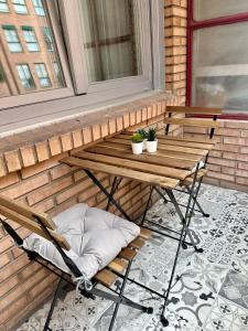 a wooden bench on a porch with two plants at Apartamento a 10 minutos de la Calle Laurel in Logroño