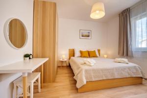 1 dormitorio con cama, mesa y espejo en Rock Apartments II, en Novalja