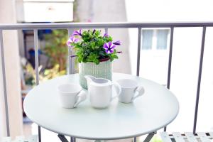 a white table with three cups and a vase with purple flowers at Dunant Studio in Athens