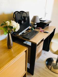 a desk with a computer and a vase with flowers at Au pied du circuit des 24h, chez Céline in Le Mans