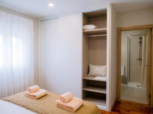 a bathroom with two folded towels on a bed at Pontes Guest House in Arcozelo
