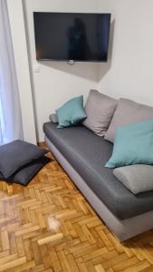 a couch with pillows sitting on a wooden floor at Dunant Studio in Athens