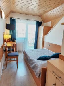 Schlafzimmer mit einem Bett, einem Schreibtisch und einem Fenster in der Unterkunft Willa Patryk in Jastrzębia Góra
