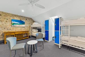 シドニーにあるLondon Plane Backpackersの二段ベッド、テーブル、椅子が備わる客室です。