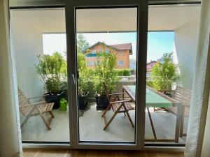Eine Glastür führt auf eine Terrasse mit einem Tisch und Stühlen. in der Unterkunft Modern Apartment, central in Bad Aibling in Bad Aibling