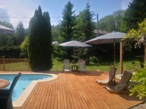 eine Terrasse mit Stühlen und Sonnenschirmen sowie einem Pool in der Unterkunft L'oree des Bornes-appartement avec piscine in Évires
