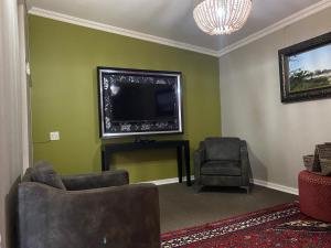 a living room with a flat screen tv and two chairs at Castello Guest House, Bloemfontein in Bloemfontein