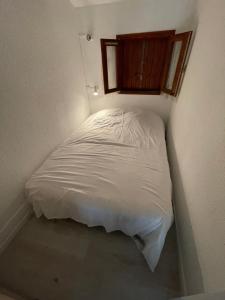 a small white bed in a room with a window at Appartement bord de mer in Sainte-Marie-la-Mer