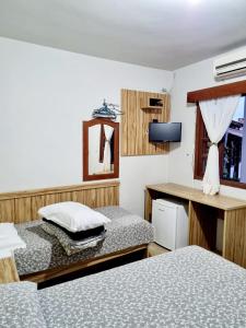 Habitación pequeña con 2 camas y escritorio. en Bartholo Plaza Hotel Santa Catarina, en Penha