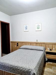 a bedroom with a bed and a table and two pictures on the wall at Bartholo Plaza Hotel Santa Catarina in Penha