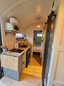 a kitchen in a tiny house with a bed at Gatwick Hideaway Hut in Charlwood