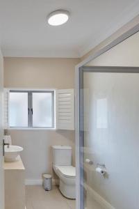 a bathroom with a toilet and a glass shower at Seafront Retreat in Sandbaai in Hermanus