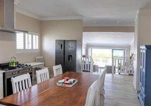 a kitchen and dining room with a wooden table with chairs at Seafront Retreat in Sandbaai in Hermanus