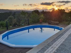a blue swimming pool on a deck with the sunset in the background at Bed and breakfast Casa d'Oliveiral - Adults Only in Aguda