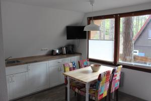 eine Küche mit einem Holztisch mit Stühlen und einem Fenster in der Unterkunft Finndorf am Strand in Trassenheide