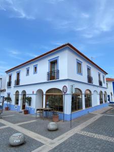 ein weißes Gebäude mit einem Tisch davor in der Unterkunft Zé Inácio - Alojamento e Restaurante in Porto Covo