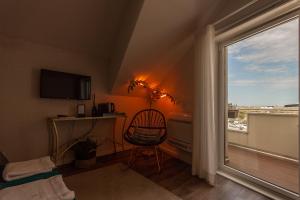 Cette chambre dispose d'une chaise et d'une fenêtre avec vue. dans l'établissement Urbana Homes by Home Sweet Home Aveiro, à Aveiro