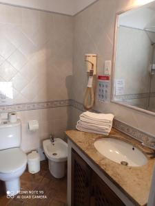 a bathroom with a sink and a toilet and a mirror at Zé Inácio - Alojamento e Restaurante in Porto Covo