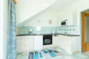 a kitchen with white cabinets and a tile floor at Appartment Isabelle Sky in Presseggersee