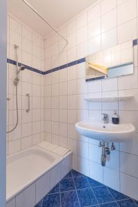a white tiled bathroom with a sink and a tub at Appartment Isabelle Sky in Presseggersee