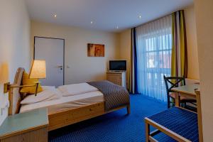 a hotel room with a bed and a desk and a television at Servus Gelting in Geretsried