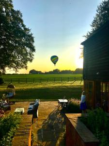 a person standing on a patio watching a hot air balloon at Mulberry Barn in Micheldever