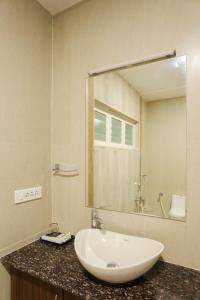 baño con lavabo y espejo grande en sri balaji grand hotel, en Kumbakonam