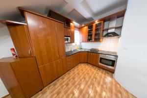 a kitchen with wooden cabinets and a wooden floor at APARTMAN NAAJ in Bihać