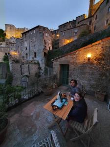 duas pessoas sentadas numa mesa em frente a um castelo em Old ceramic factory close to Unesco itineraries em Sorano