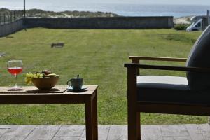 una mesa con una copa de vino y una silla en Casa Lobadiz, en primera línea de playa, Doniños, en Vila Da Area