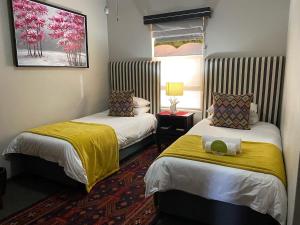 a hotel room with two beds and a window at Castello Guest House, Bloemfontein in Bloemfontein
