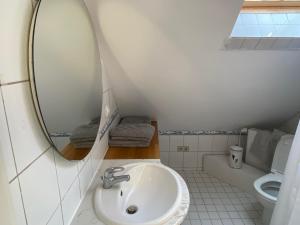 a bathroom with a sink and a mirror and a toilet at Kaptainshuus Apartment A in Leer