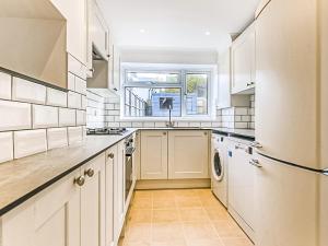 a kitchen with white cabinets and a window at Sahara Rose in East Grinstead