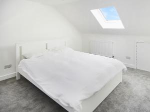 białe łóżko w białej sypialni z oknem dachowym w obiekcie Sahara Rose w mieście East Grinstead