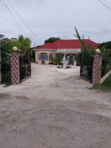 a house with a gate in front of a driveway at Eliwes Villa in Treasure Beach