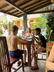 een groep jongeren die aan een tafel zitten bij Werkudara Guest House in Ubud