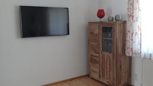 a flat screen tv on a wall next to a wooden cabinet at Ferienwohnung Funk in Langenargen